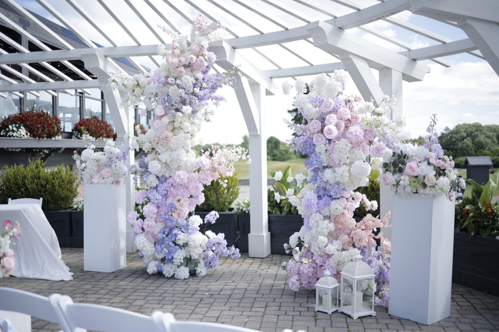 Tall floral columns framing a ceremony under a white pergola.