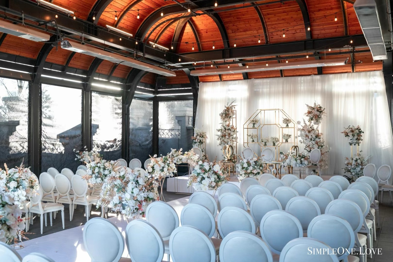 A ceremony set under a timber-beamed roof with pale blue chairs.