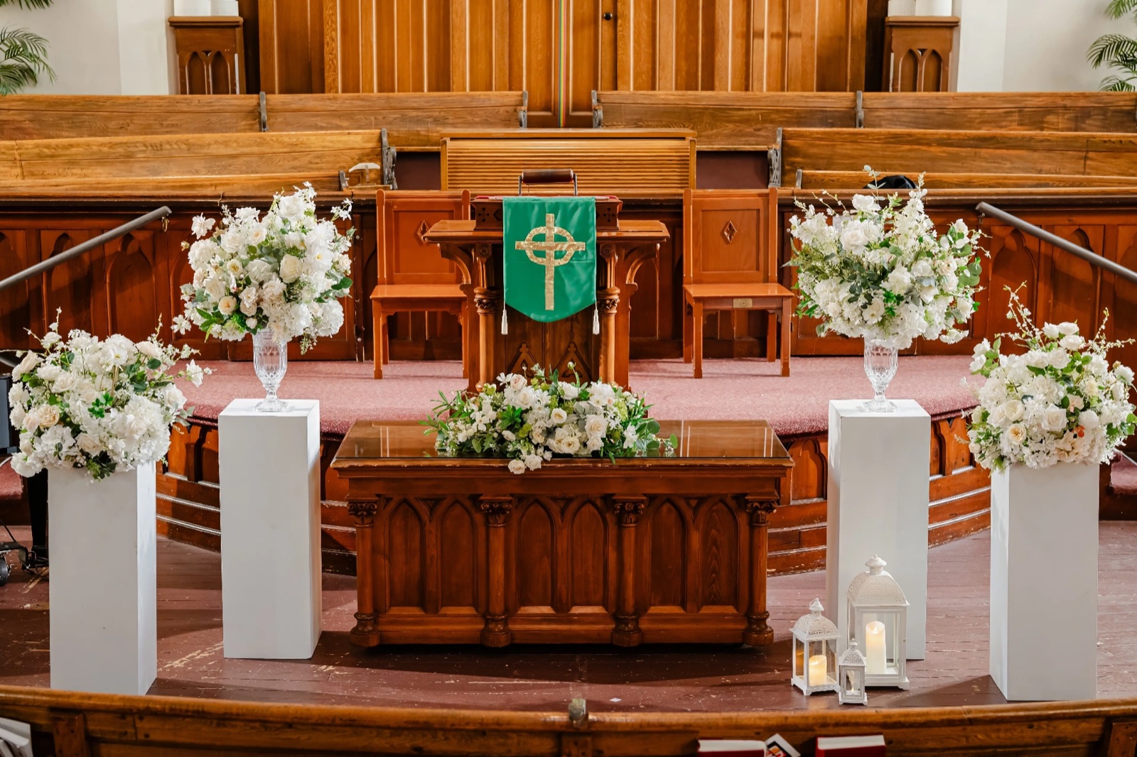 A church sanctuary dressed with white flowers on pedestals.