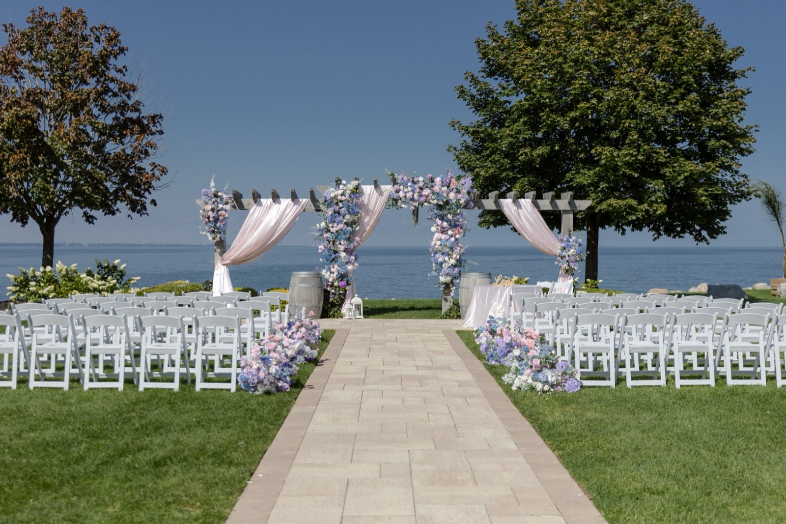 A lakeside ceremony on the lawn, chairs facing the water.