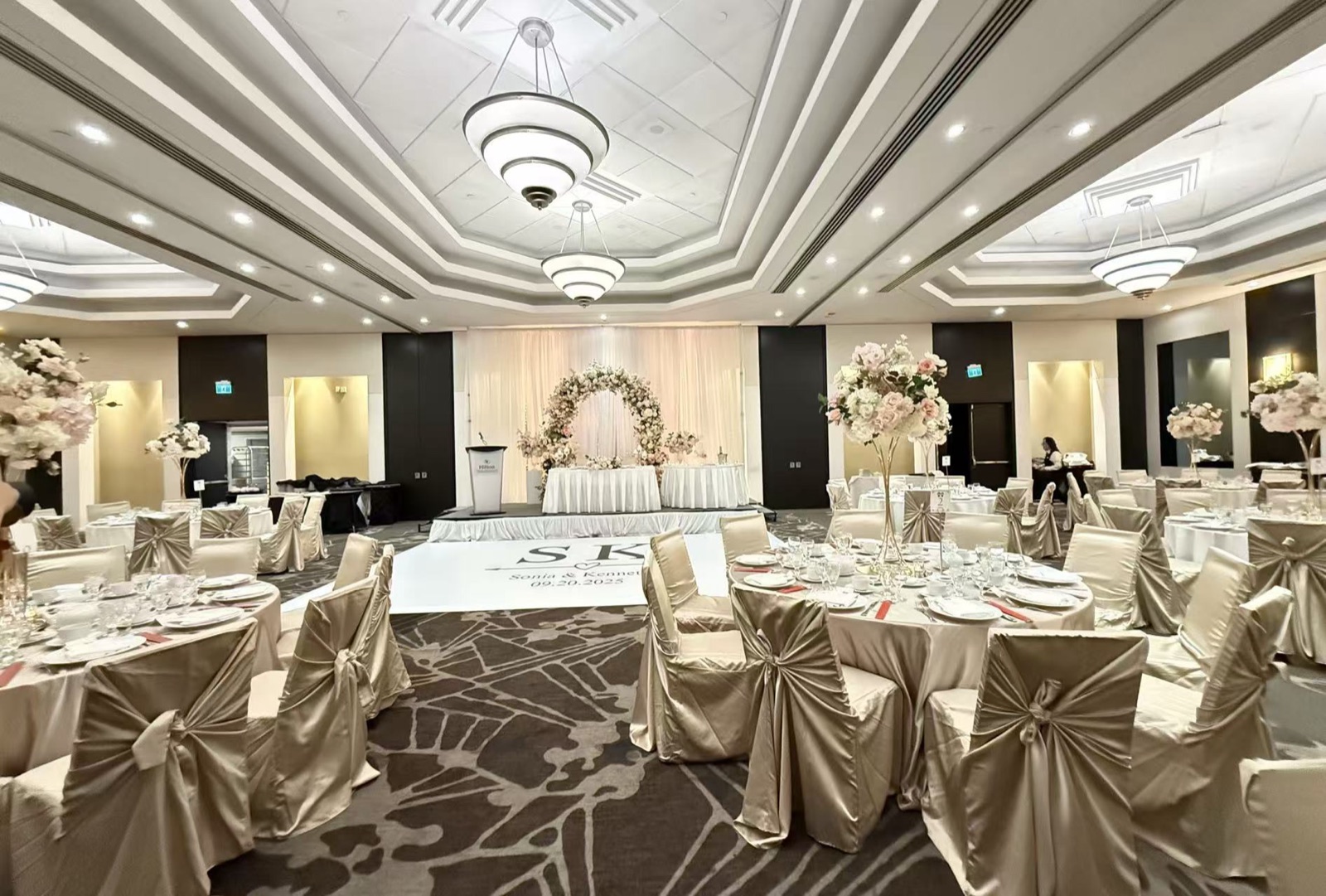 A banquet hall set with chair covers and centrepieces.