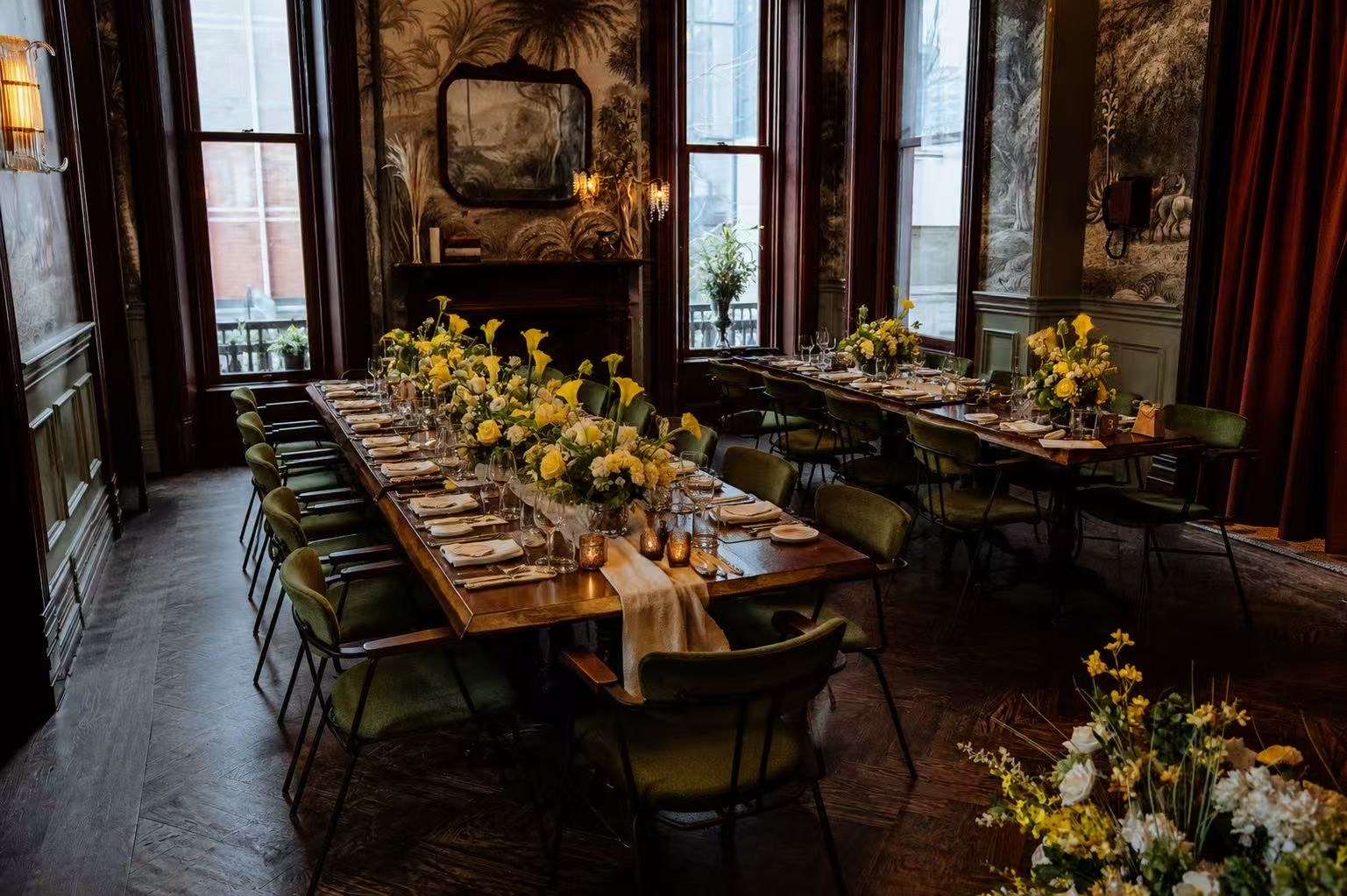 A long candlelit table in a panelled private dining room.