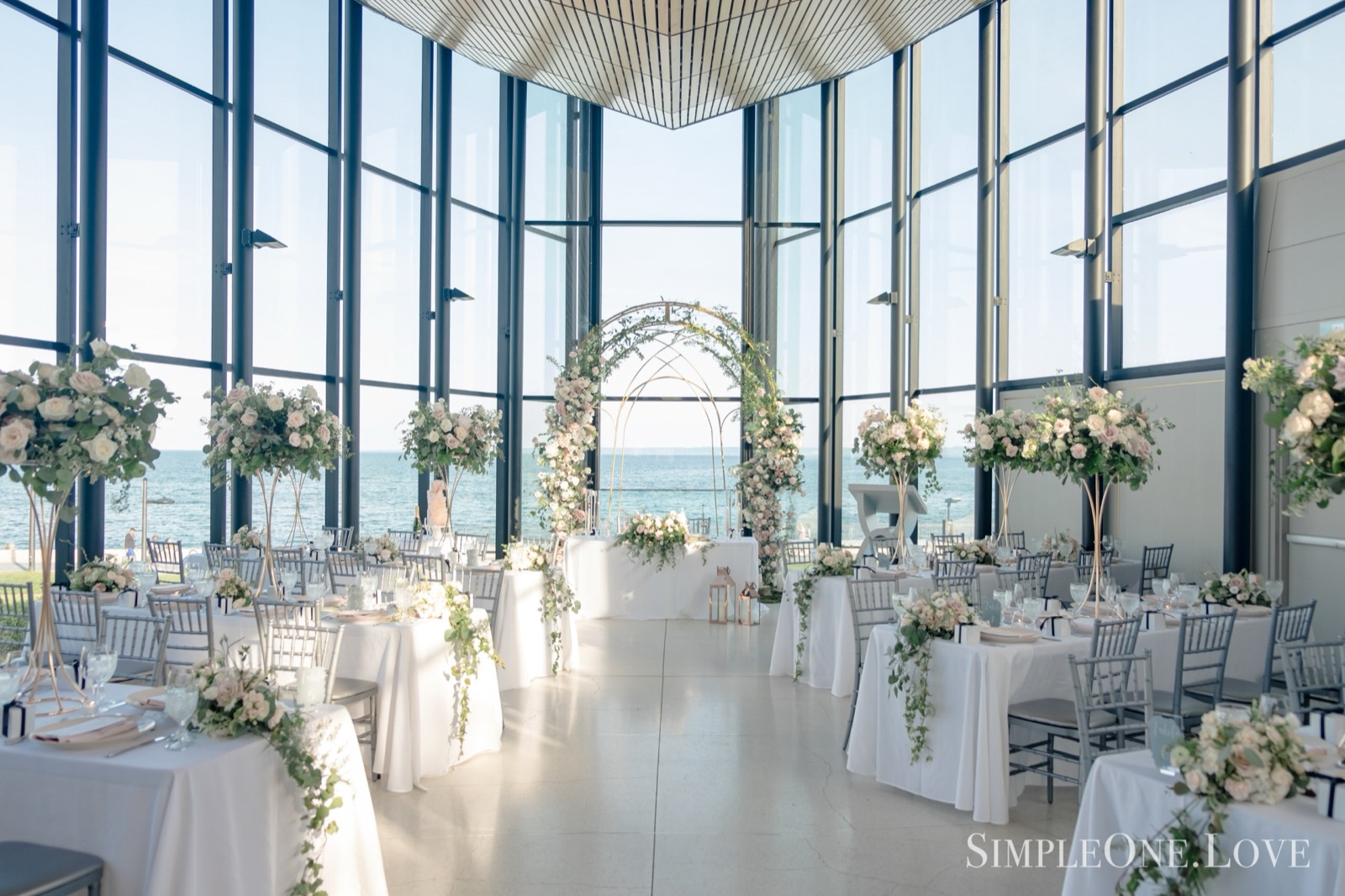 A glass-walled room above the water, set for dinner.