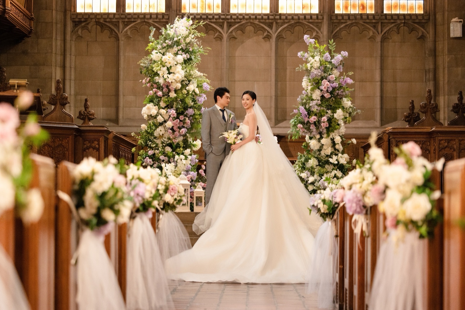 A couple between flower pillars in a Gothic hall.
