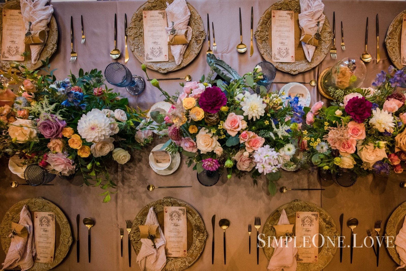 Seen from above: a long table of flowers, gold chargers and place cards.