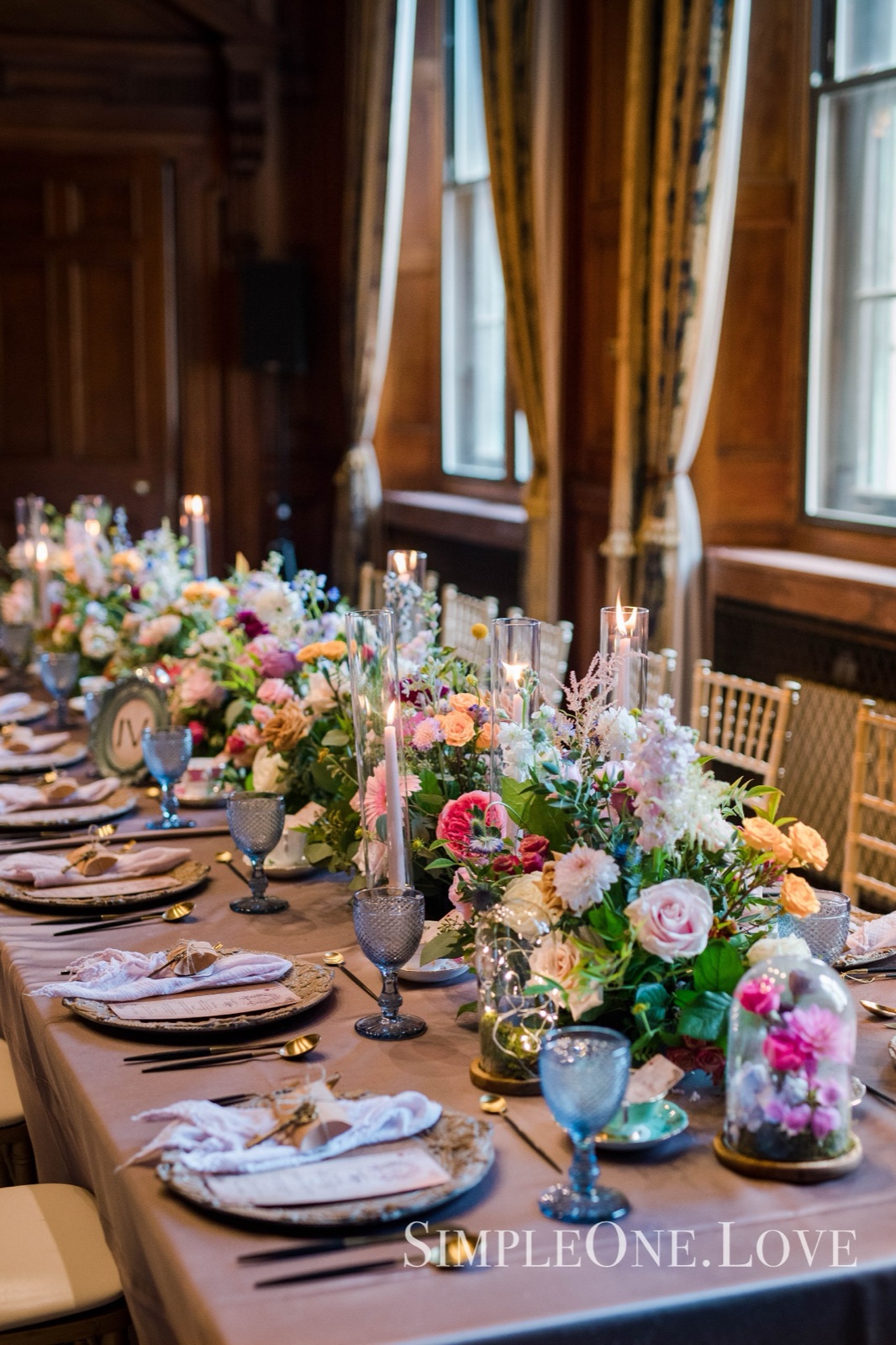 A long table crowded with flowers, glassware and candles.