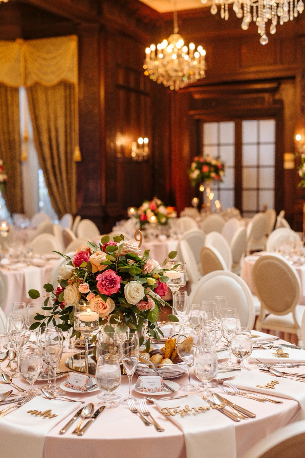 A round table under a chandelier in a wood-panelled room.