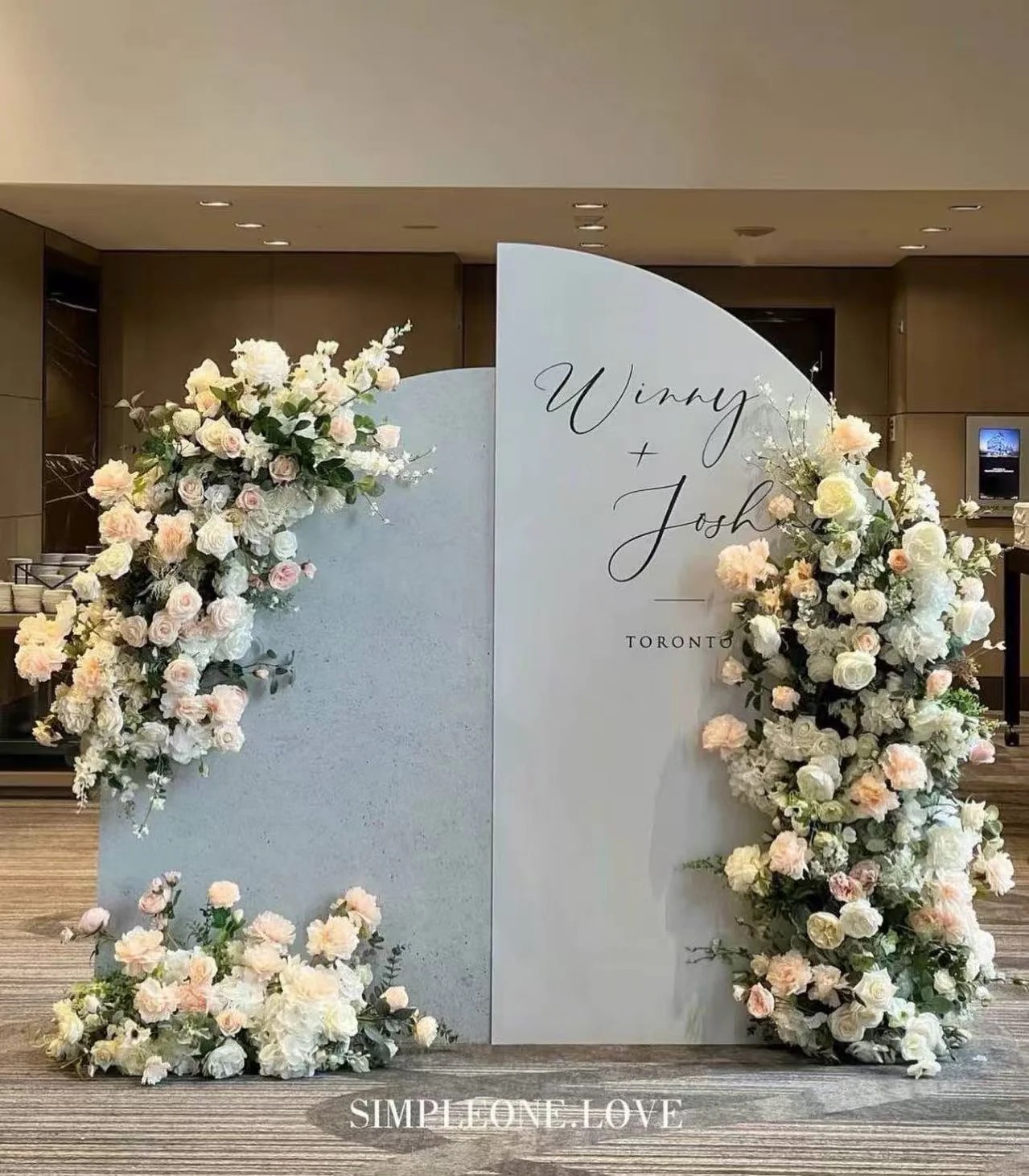 A painted welcome sign with the couple's names, framed by flowers.