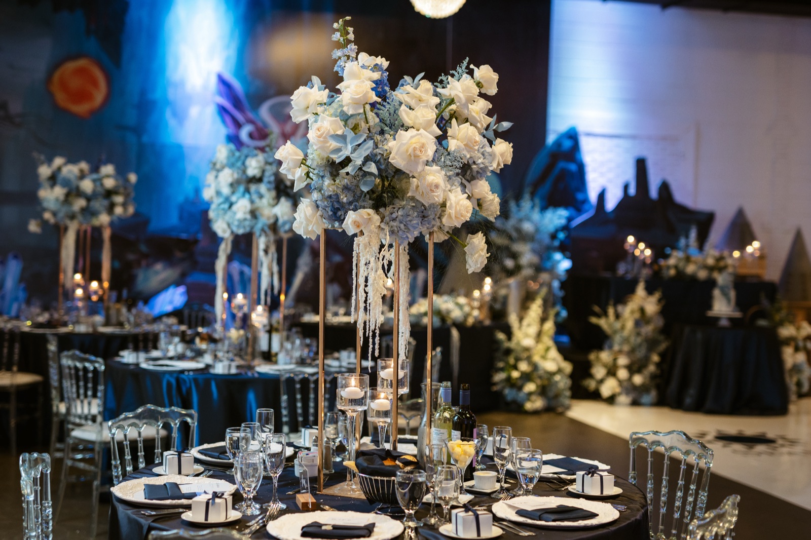 Tables in low blue light, set for a late reception.
